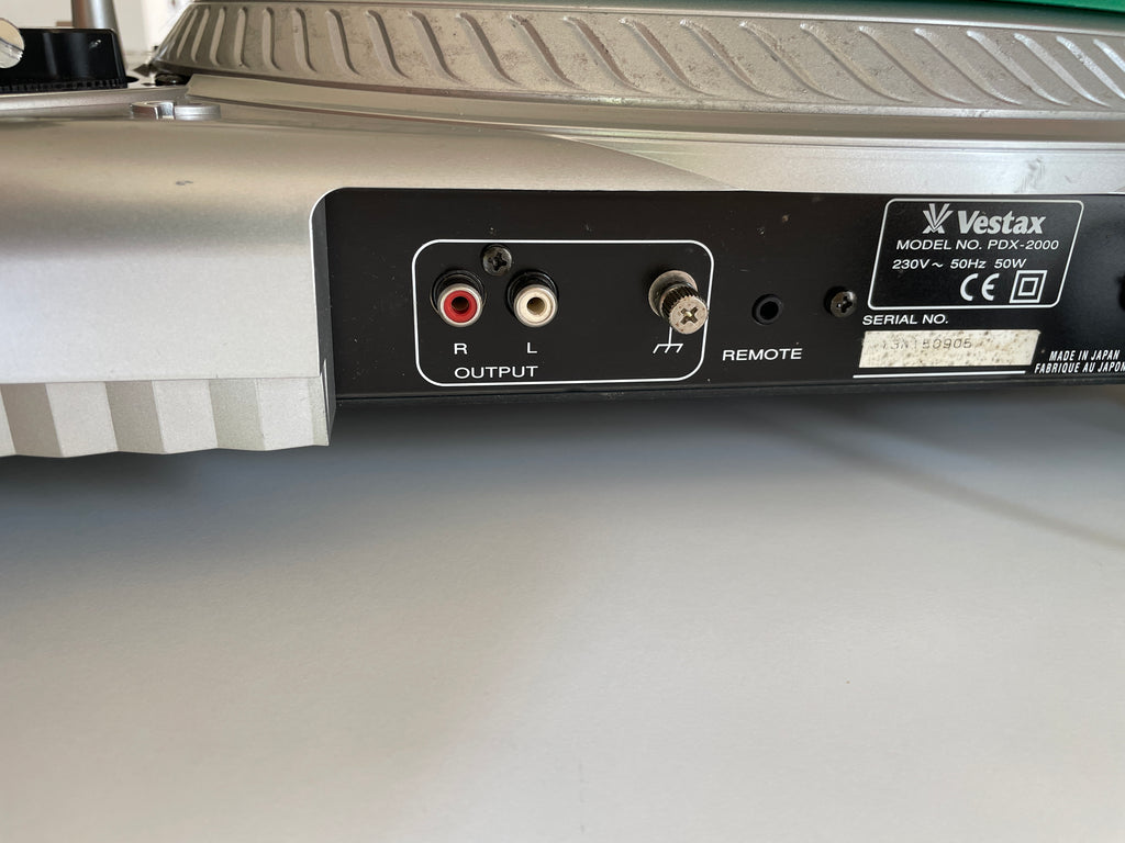 Close-up of the rear output panel of a Vestax turntable, showing red and white RCA jacks, a remote switch, and the Vestax model label.