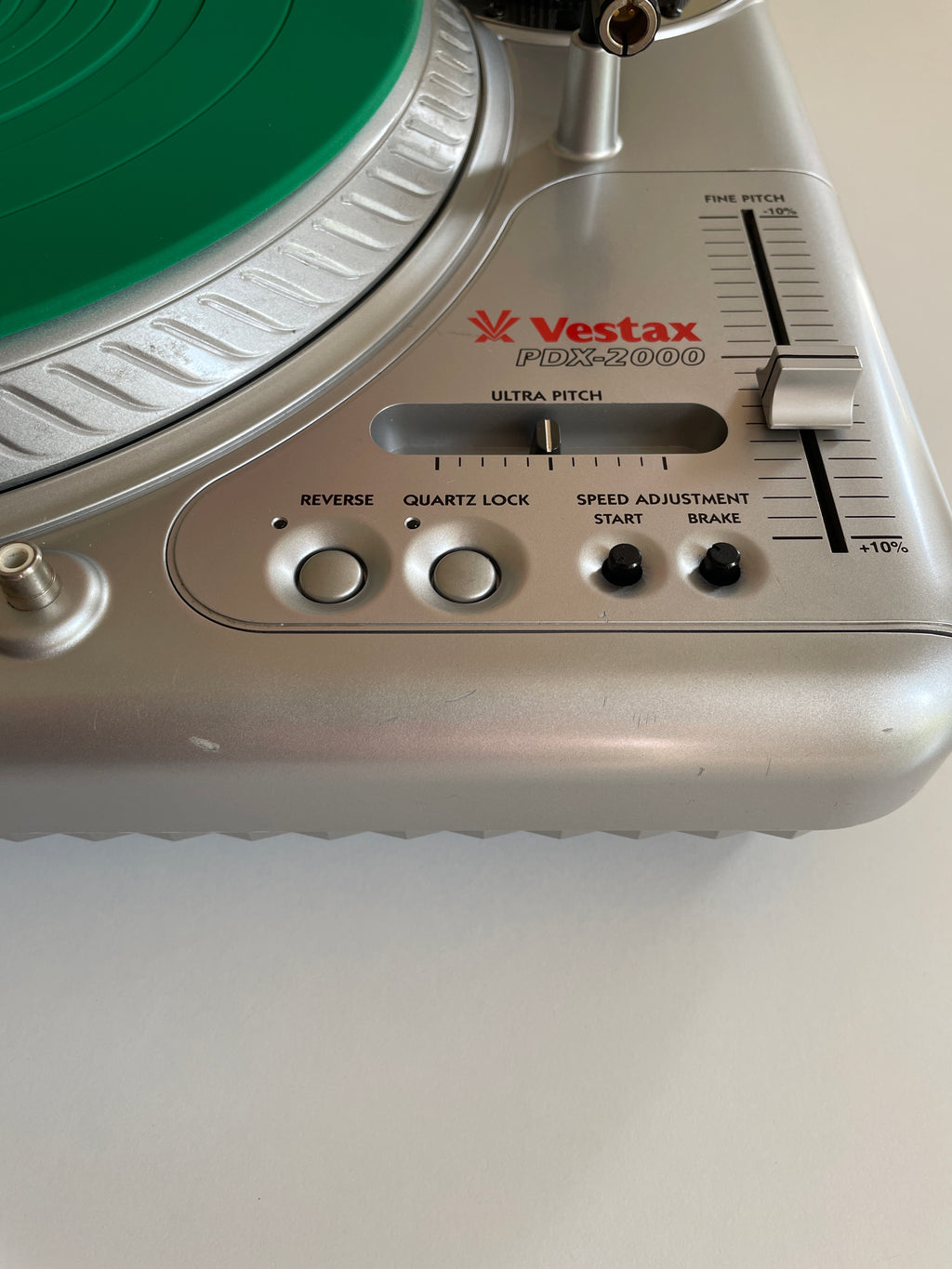 Close-up of a Vestax FX-2000 turntable showing the silver control panel, green platter, and speed adjustment dial.