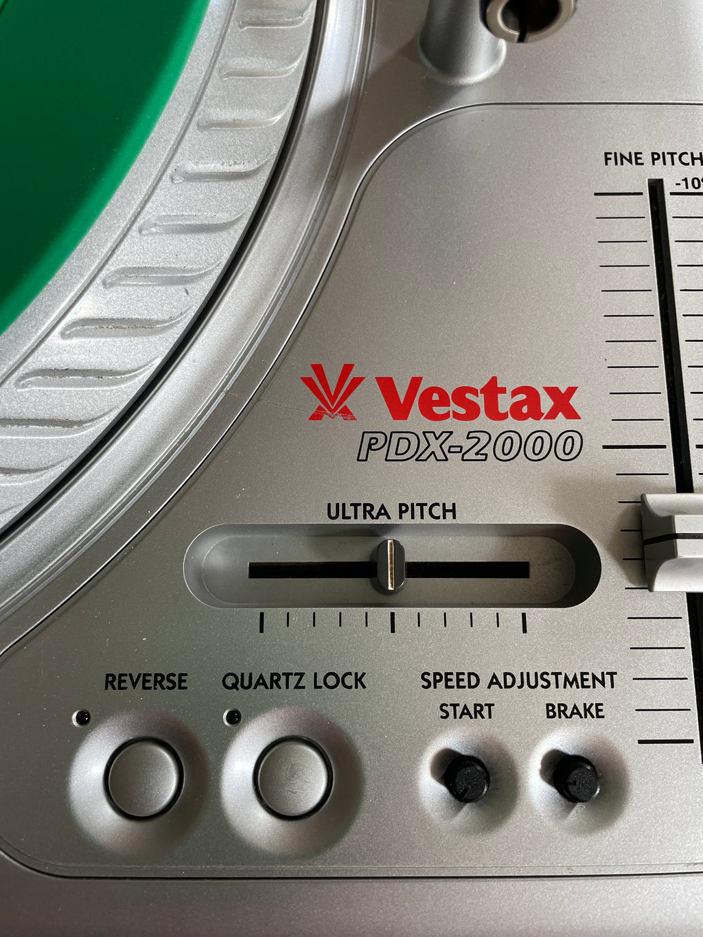 Close-up of a Vestax PDX-2000 turntable control panel showing the ultra-pitch slider, reverse and quartz lock buttons, and speed adjustment controls.