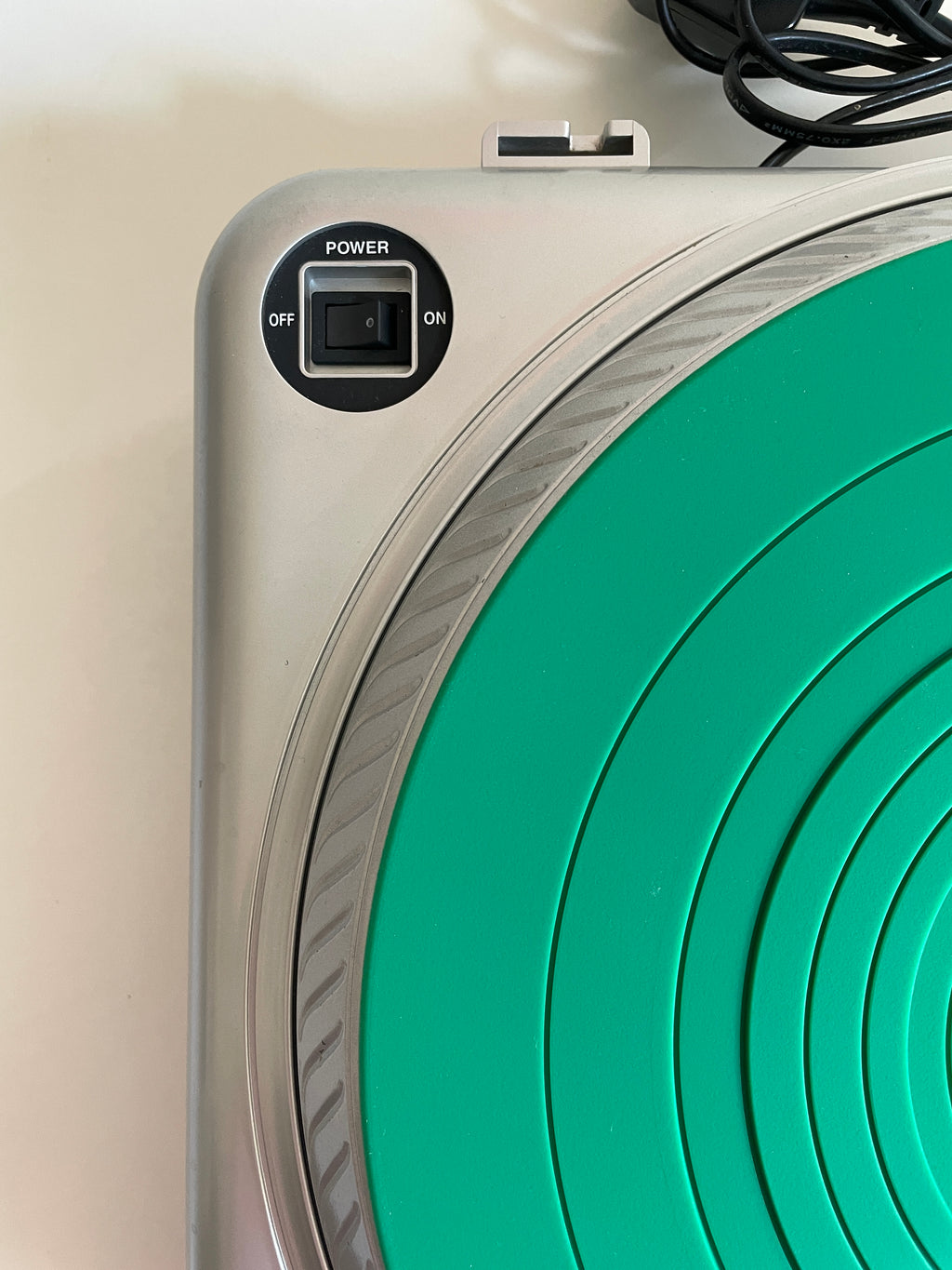 Close-up of a silver electronic device with a circular green target pad and a black power switch labeled OFF and ON.