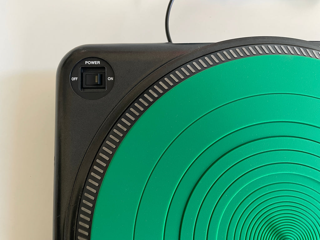 Close-up of a black electronic device with a large green circular panel featuring concentric circles and a power switch labeled OFF, ON, and POWER.