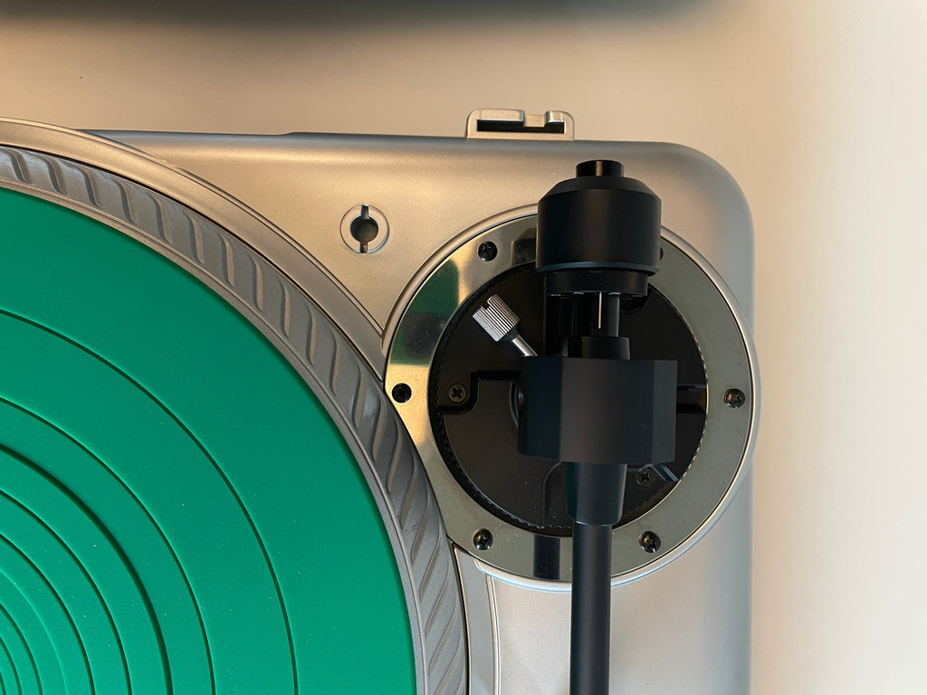 Close-up of a silver and black audio component or speaker assembly with a circular green ring visible in the lower portion.