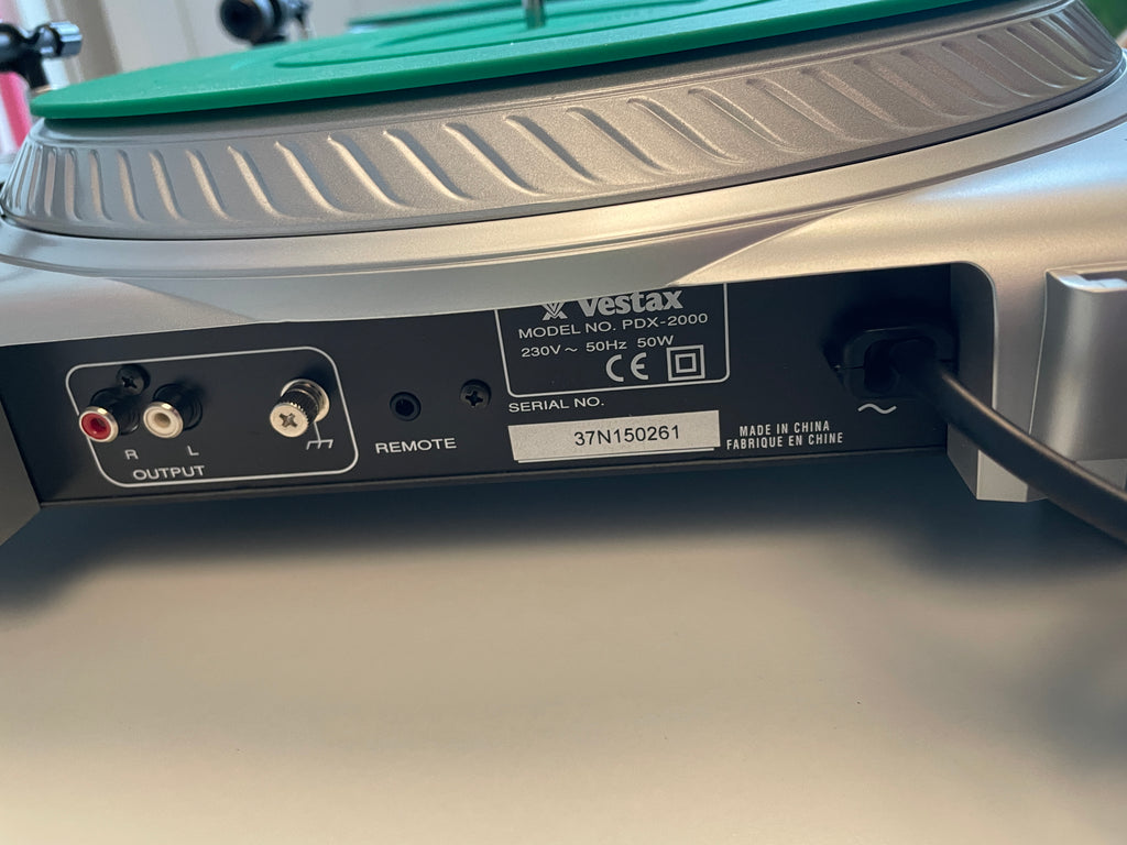 Close-up of the rear panel of a Vestax PDX-2000 turntable, showing the power cord, RCA output jacks, remote switch, and product model label.