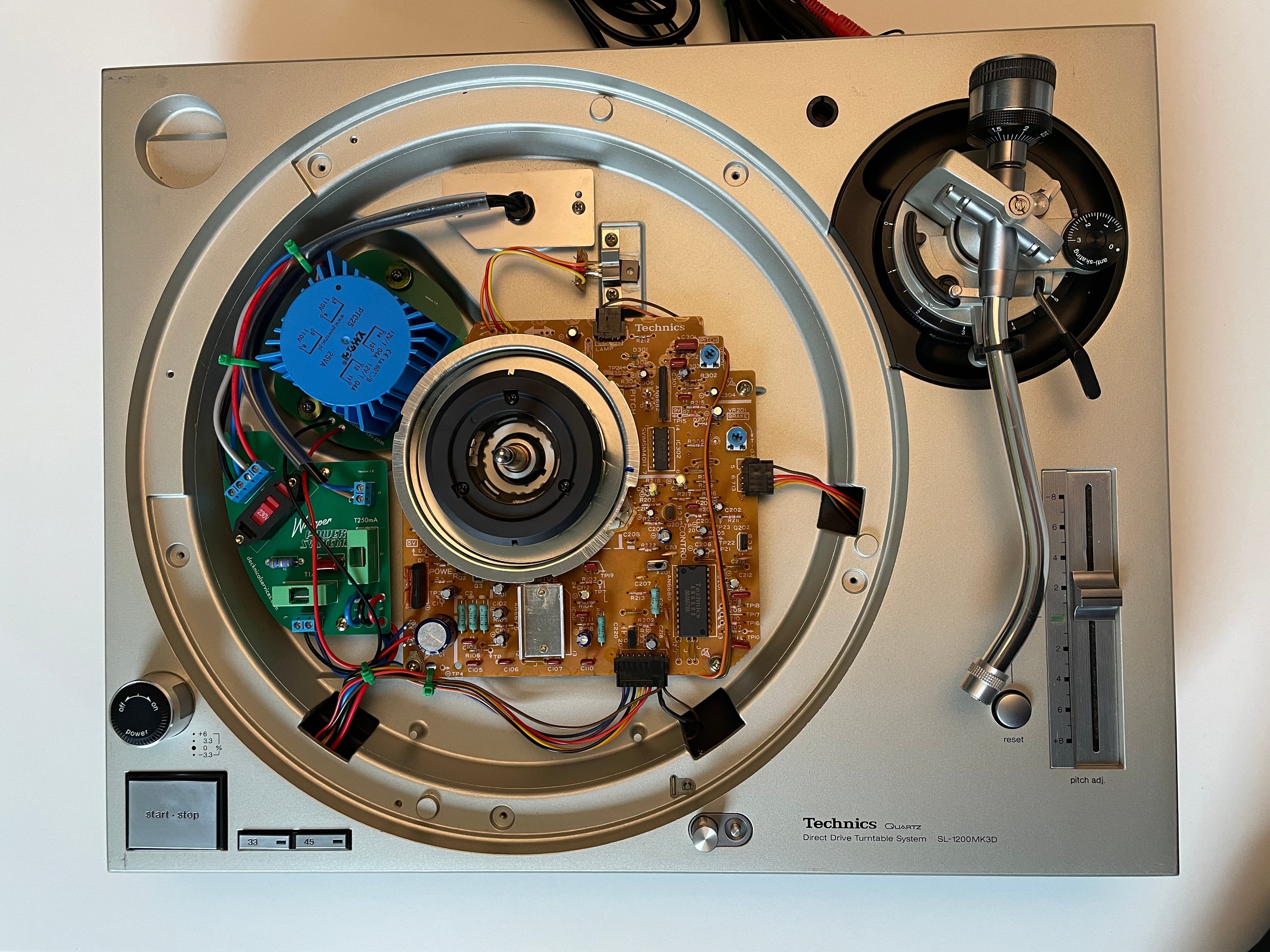An open, top-down view of a vintage Philips turntable showing its internal electronics, circuit boards, wiring, and the tonearm assembly.
