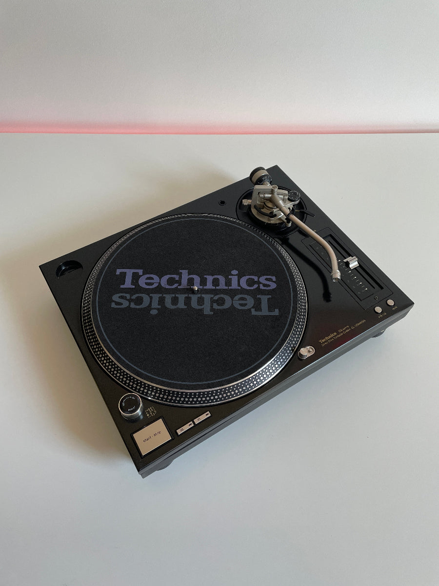 Technics turntable on a white surface with a red light in the background