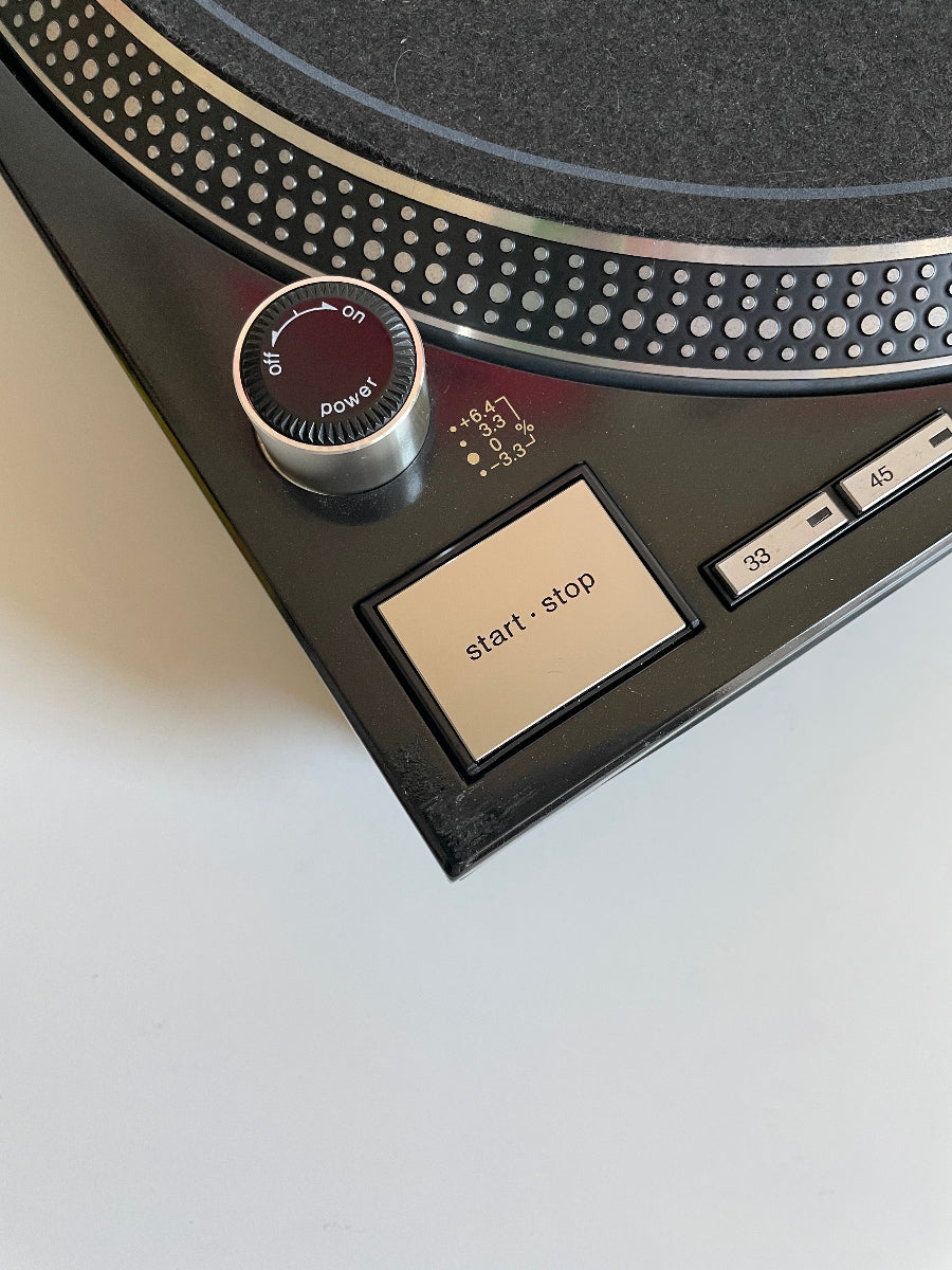 Close-up of a vintage record player control panel with 'play', 'pause', and 'stop' buttons.