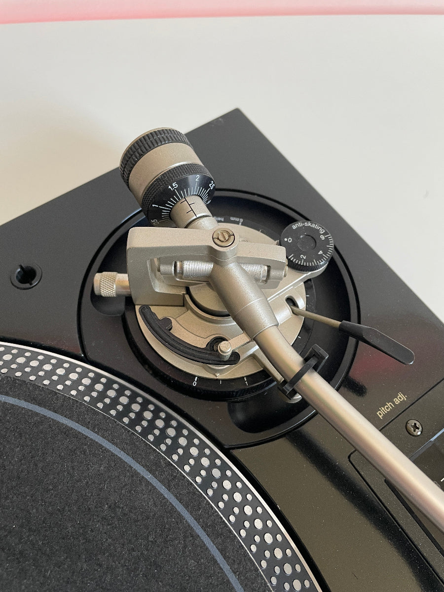 Close-up of a turntable with a needle on a light pink background