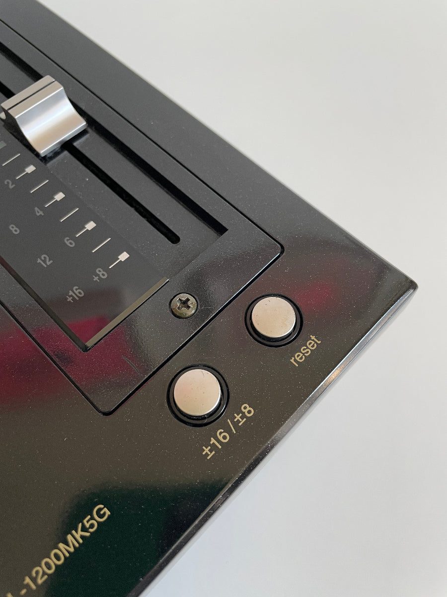 Close-up of a vintage electronic device with buttons and a dial on a light gray background