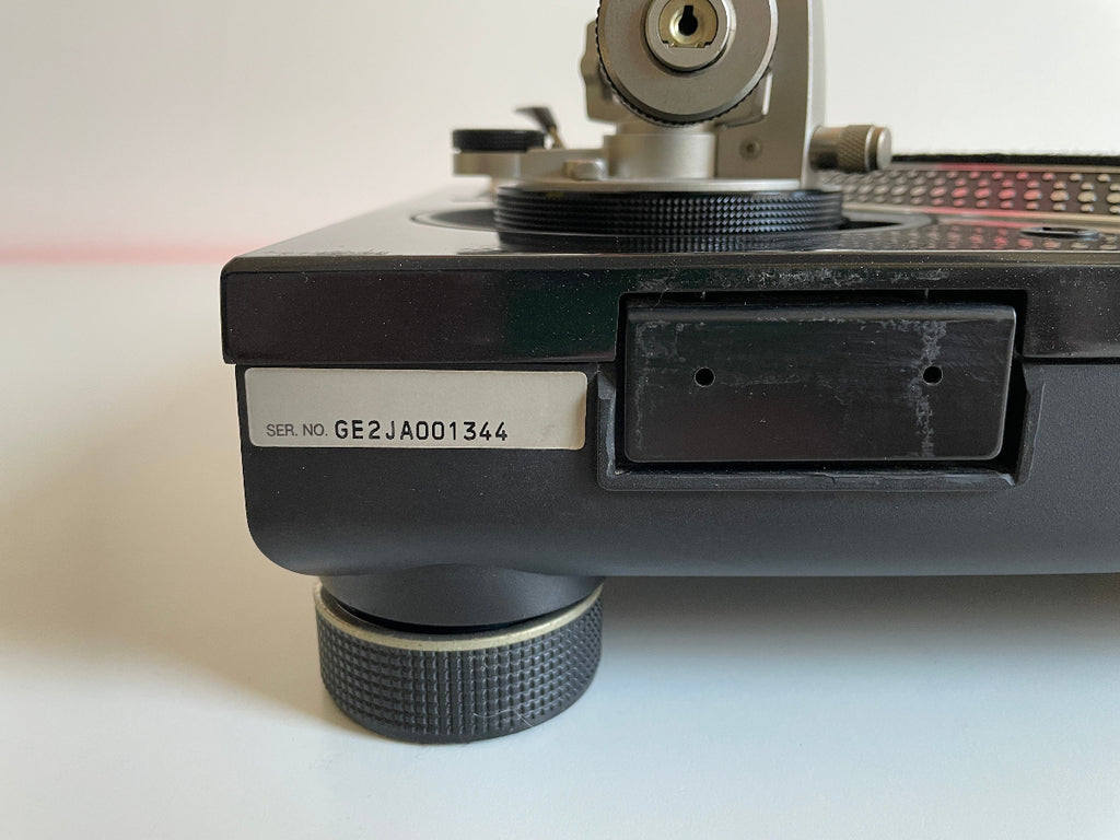 Close-up of a record player with a visible serial number on a white background