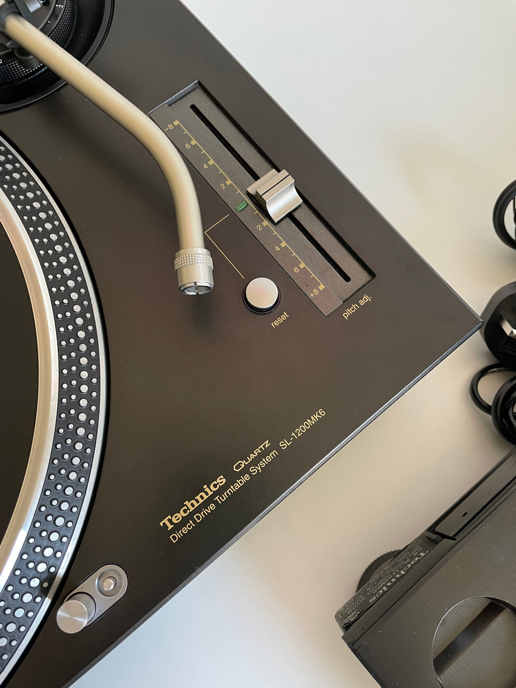 Close-up of a turntable with a focus on the control panel and cartridge.