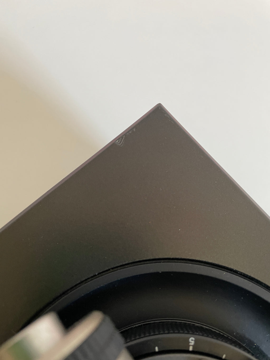 Close-up of a black electronic device with a circular component on a light gray background