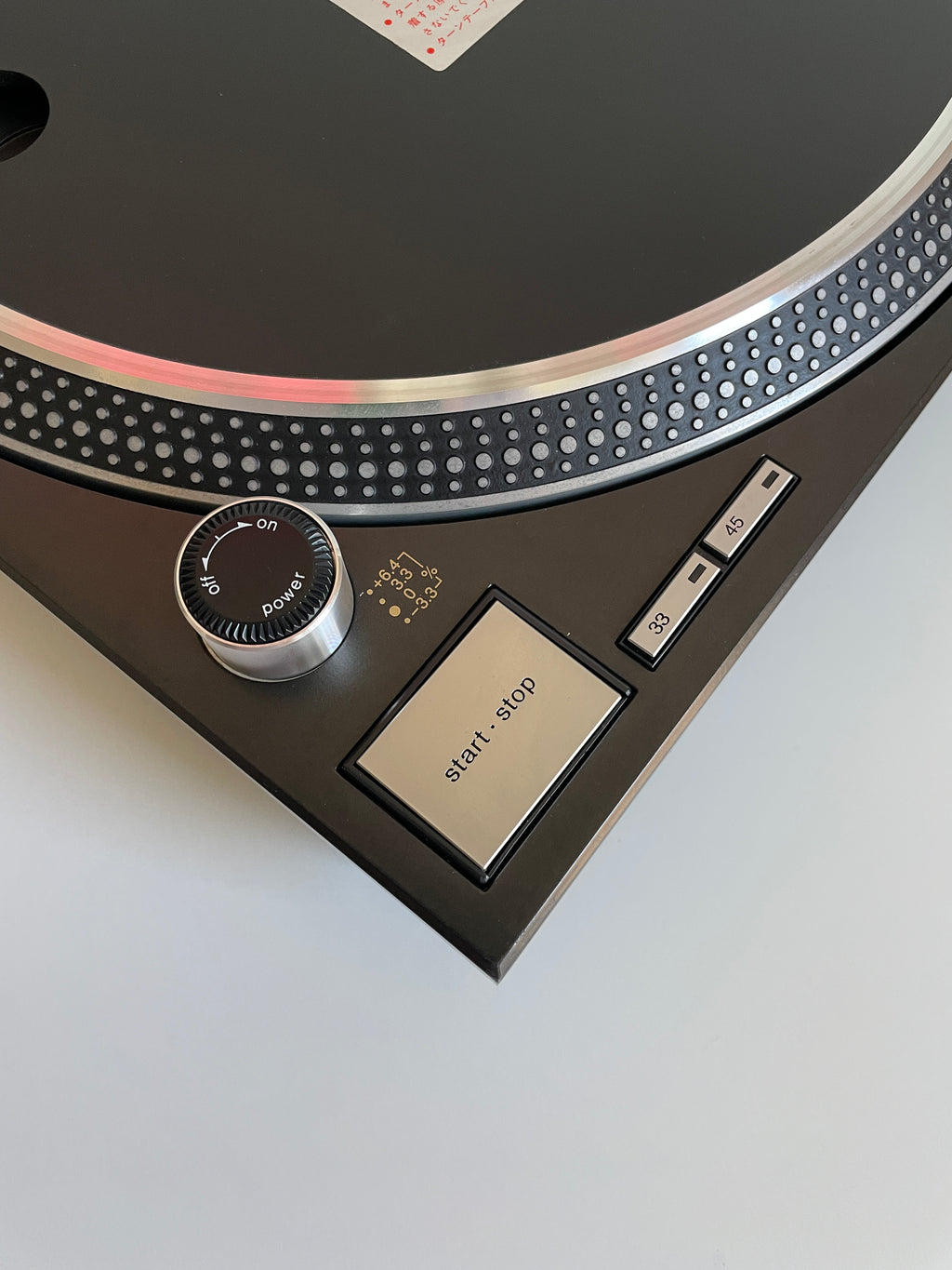 Close-up of a turntable with control buttons on a light gray background