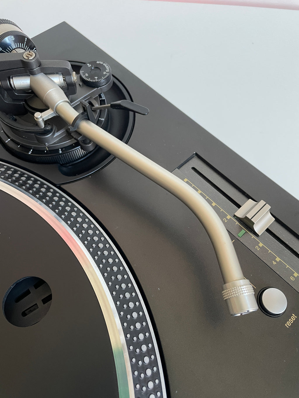 Close-up of a turntable with a tonearm on a light gray background