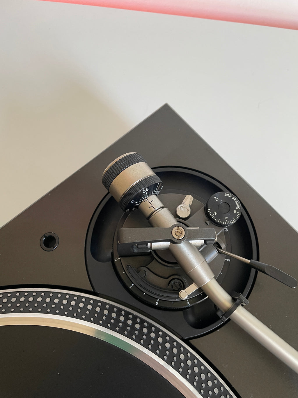 Close-up of a turntable with needle and platter on a light background