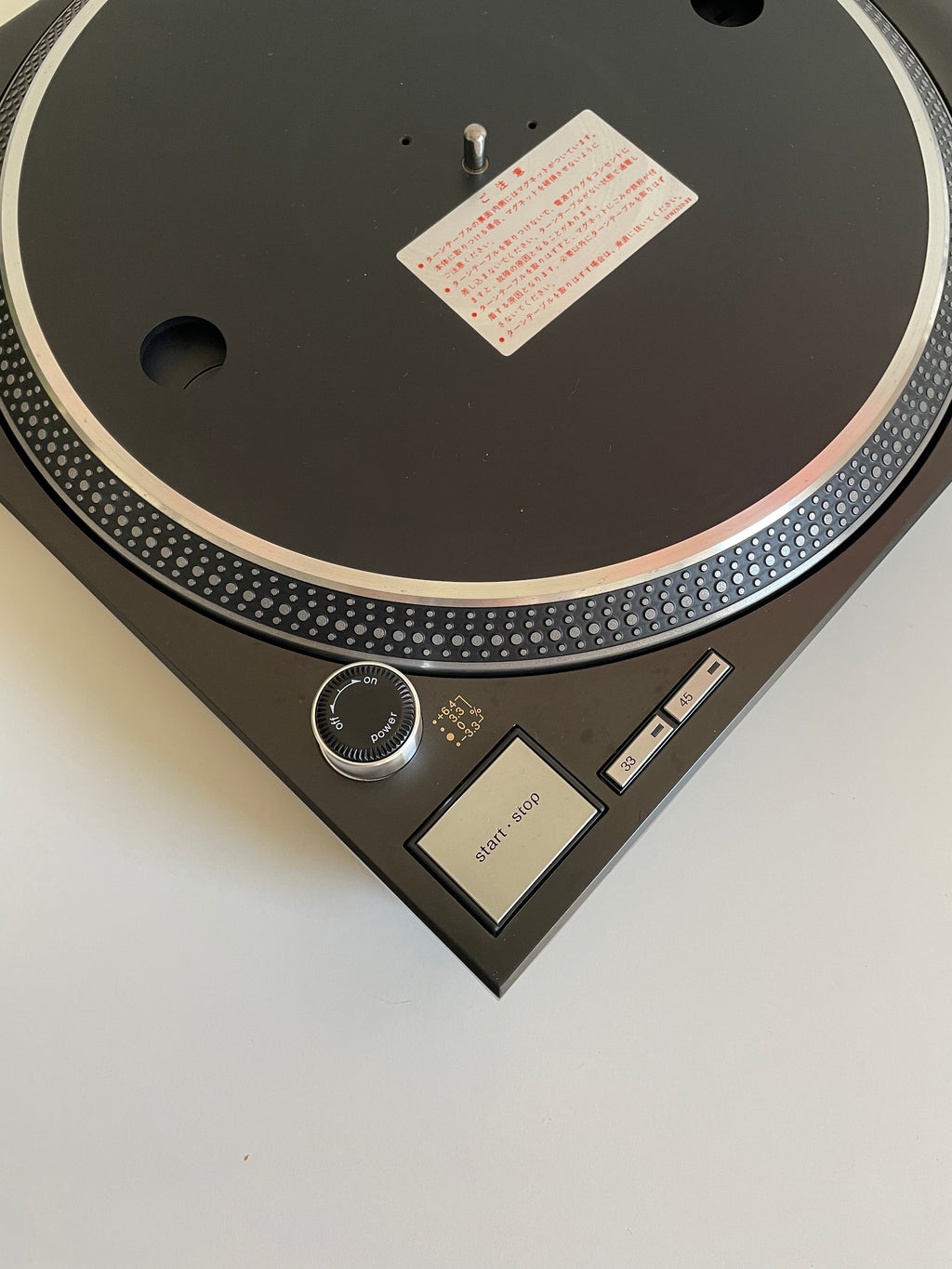 Close-up of a turntable with a white label on a light gray background