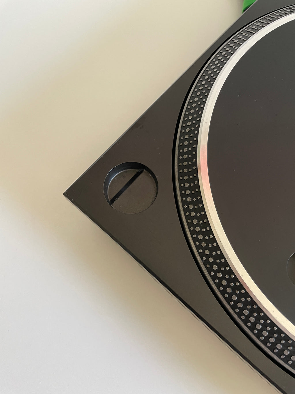 Close-up of a black electronic device with circular design on a beige surface