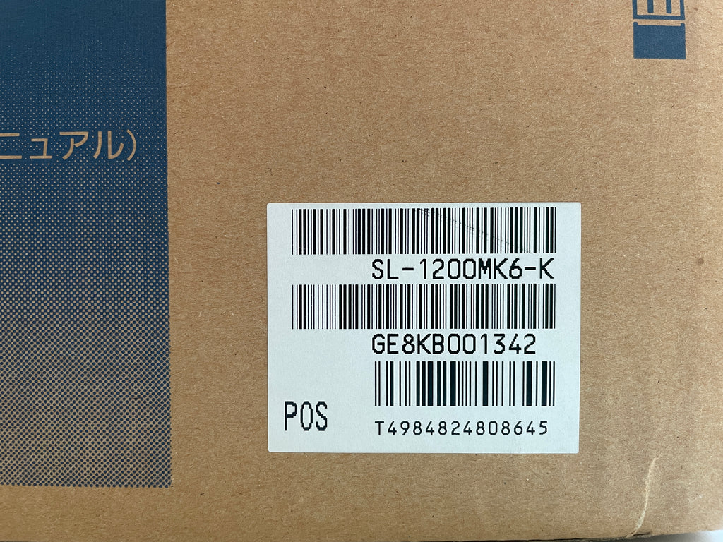 Barcode label on a cardboard surface with text and numbers.