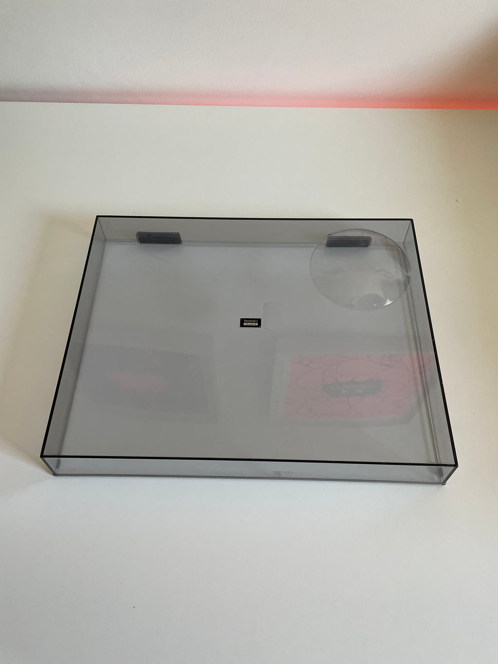 Clear plastic box with a black border on a white wall