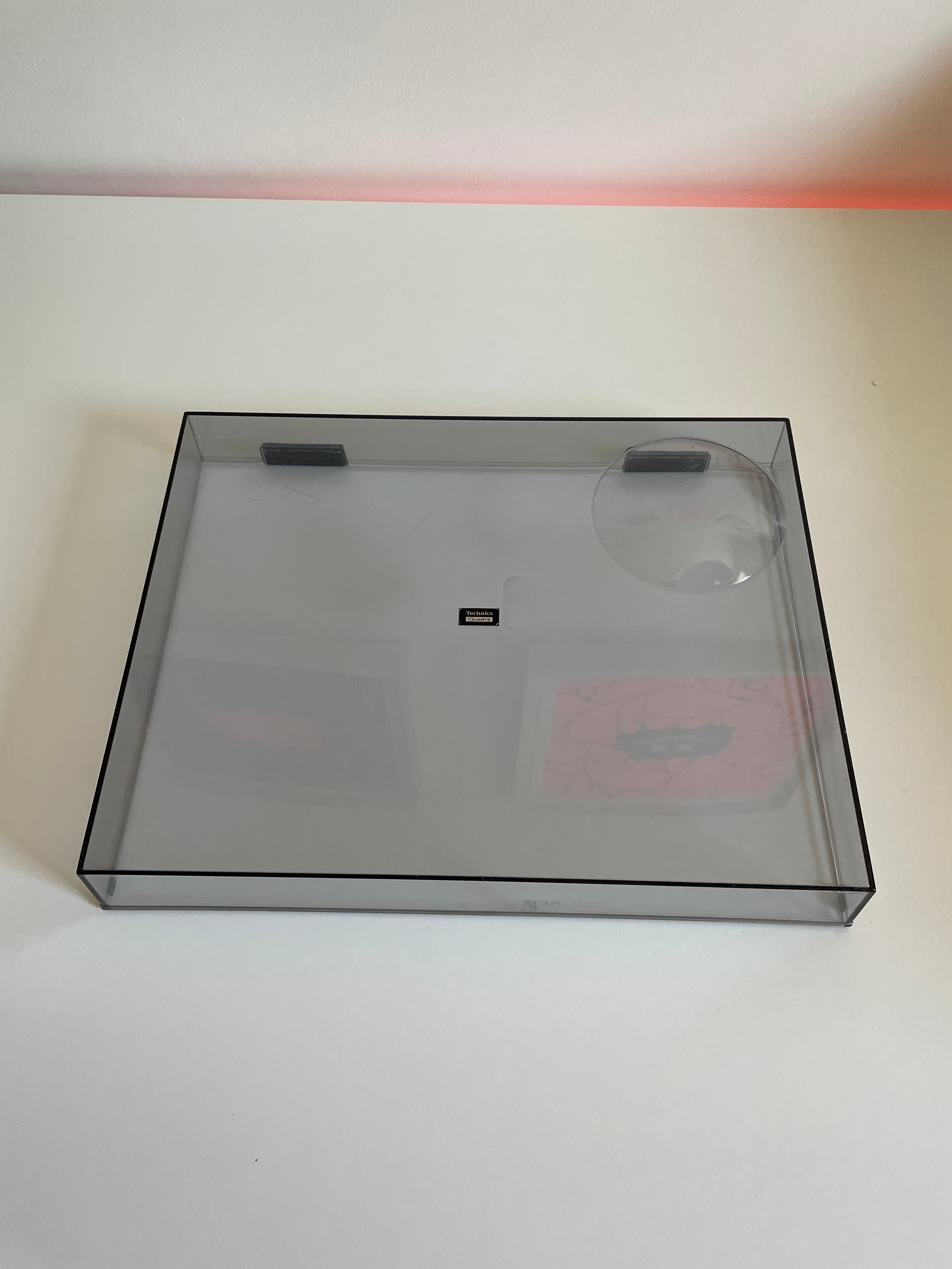 Clear plastic box with a black border on a white wall