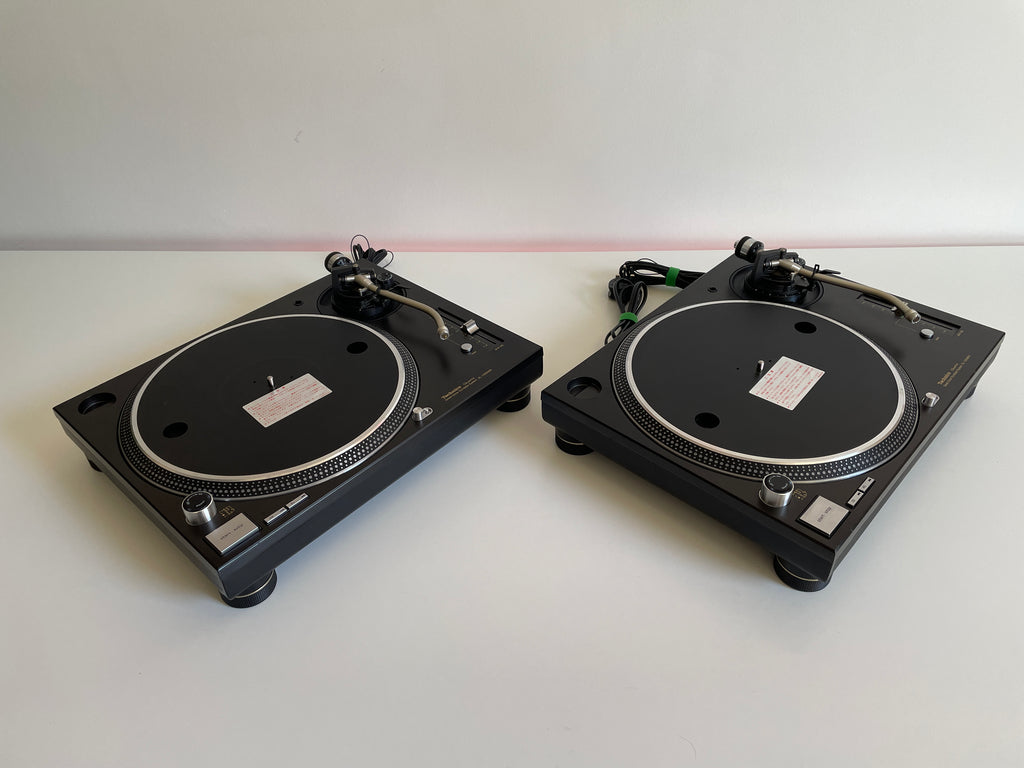 Two black turntables on a white surface with a white background