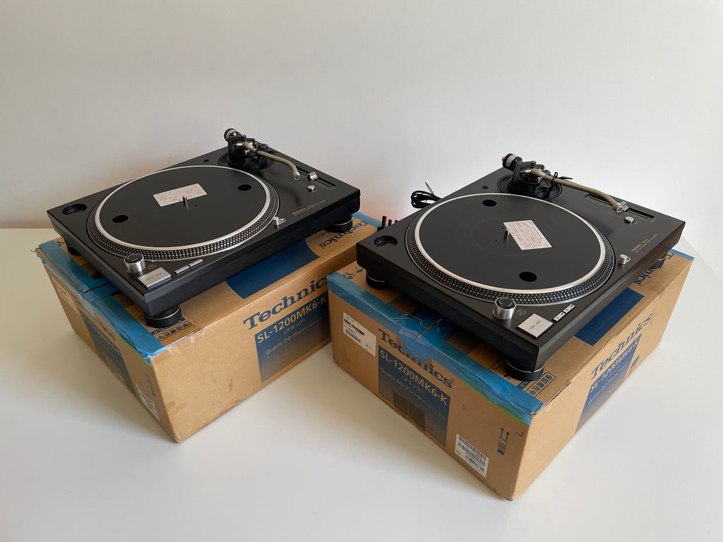 Two Technics turntables on cardboard boxes against a white background