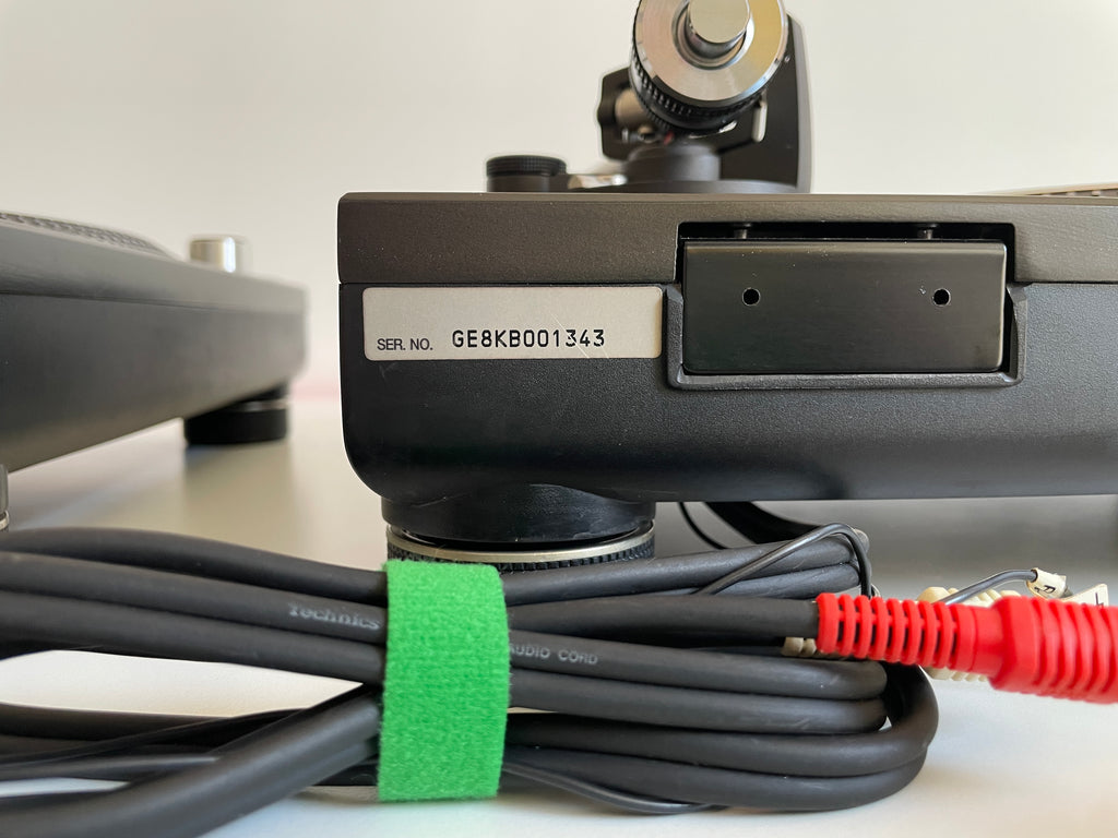 Close-up of a turntable with cables and a visible serial number label.