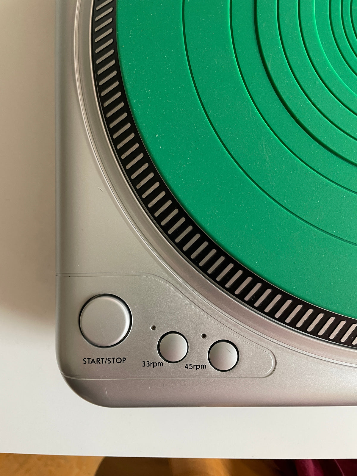 Close-up of a silver and green portable radio or speaker control panel with three round buttons labeled 30rpm, 45rpm, and START/STOP.