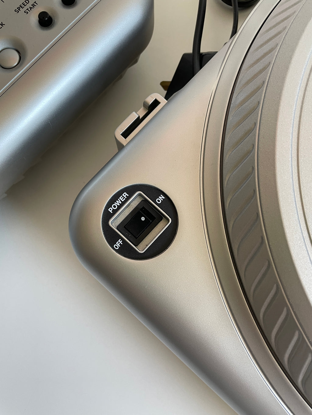 Corner of silver turntable showing the on/off switch