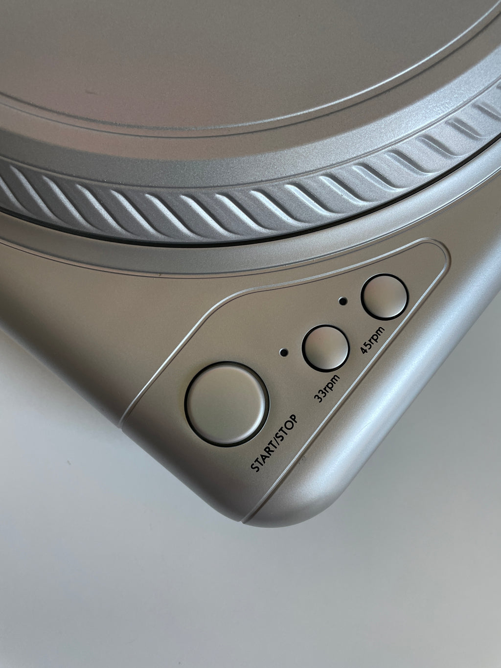 Close-up of a turntable with control buttons on a light gray background