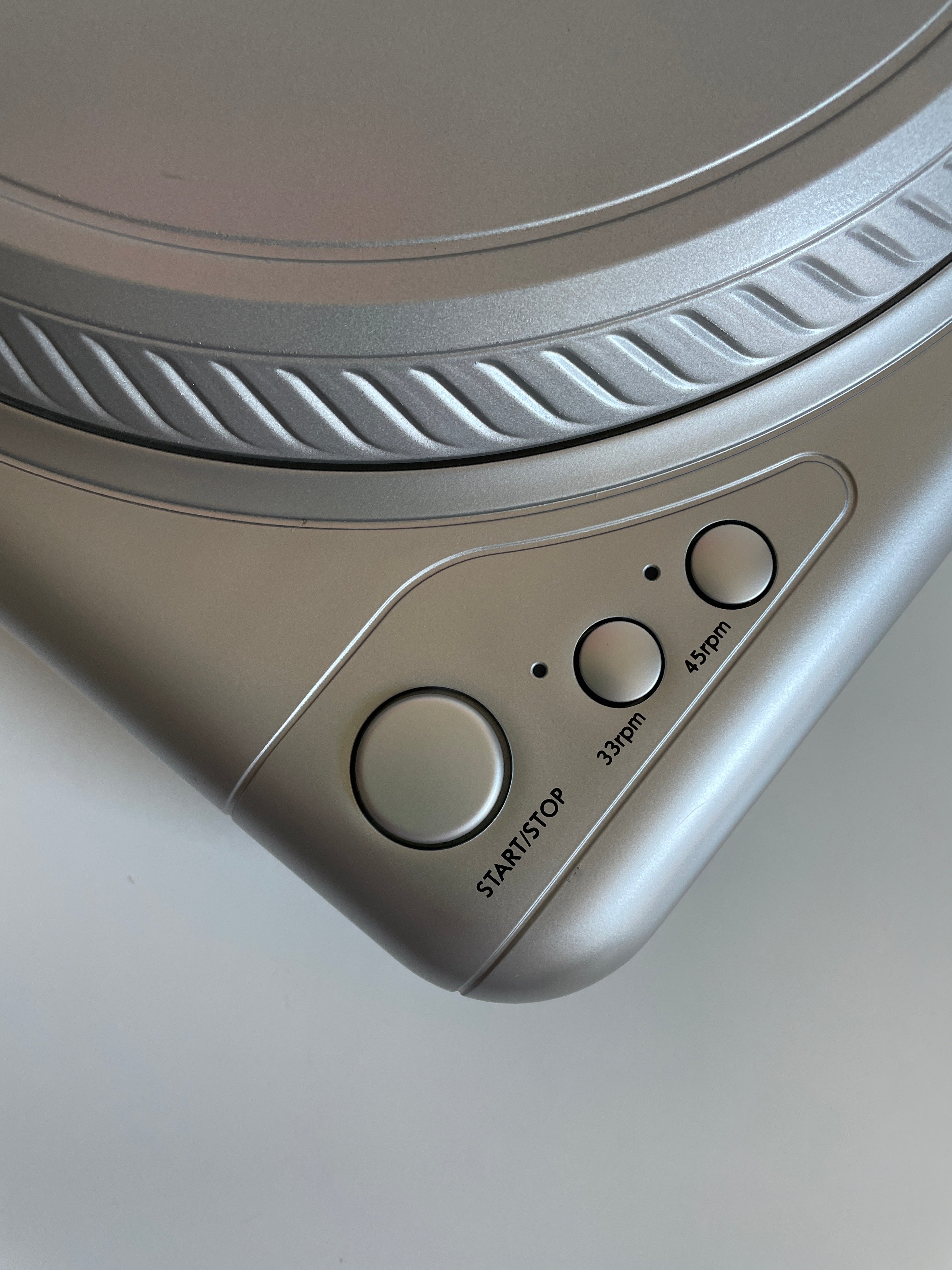 Close-up of a turntable with control buttons on a light gray background