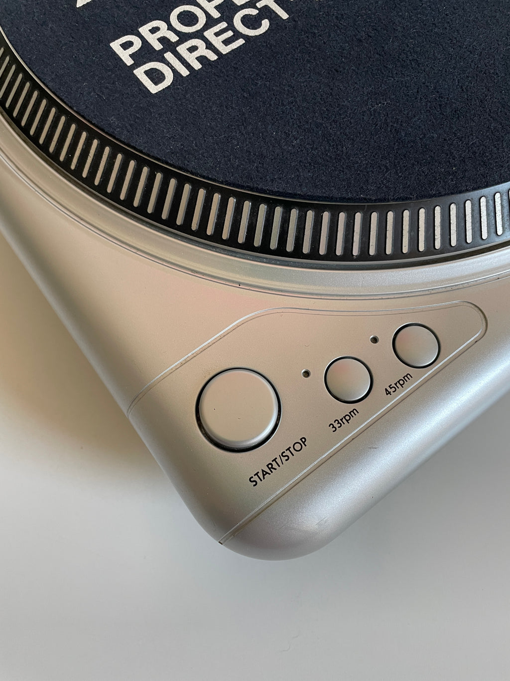 Close-up of a turntable with control buttons on a neutral background