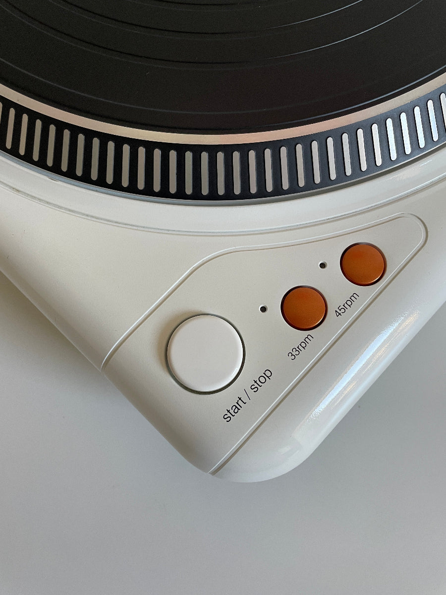 Close-up of a vintage record player with orange control buttons on a gray background