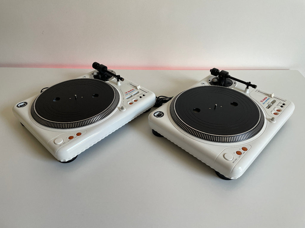 Two white turntables on a light gray surface with a white background