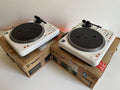 Two white turntables on cardboard boxes with a plain background