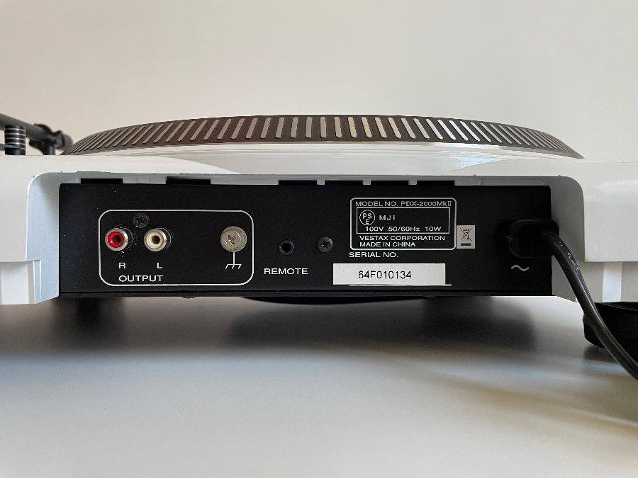 Back view of a turntable with audio connectors on a white surface